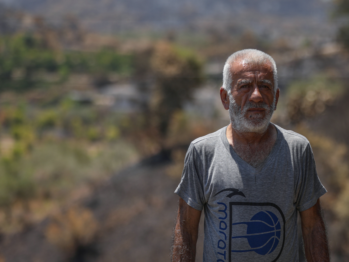 Zaki* standing in a burned area near his home in Syria.
