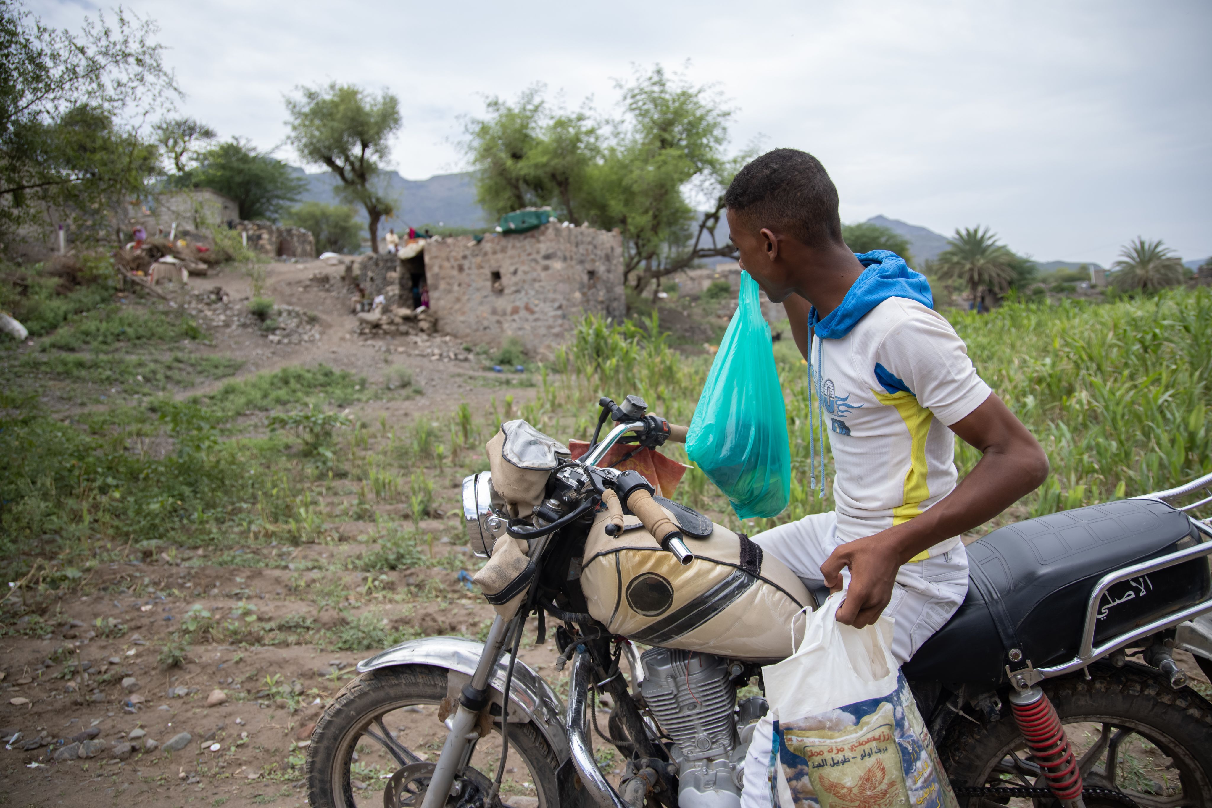 Munadhel rides the motorbike that he was able to purchase with the stipend he received during the internship he completed as part of an Oxfam project. He uses the motorbike to sell fruit and vegetables to earn additional income.